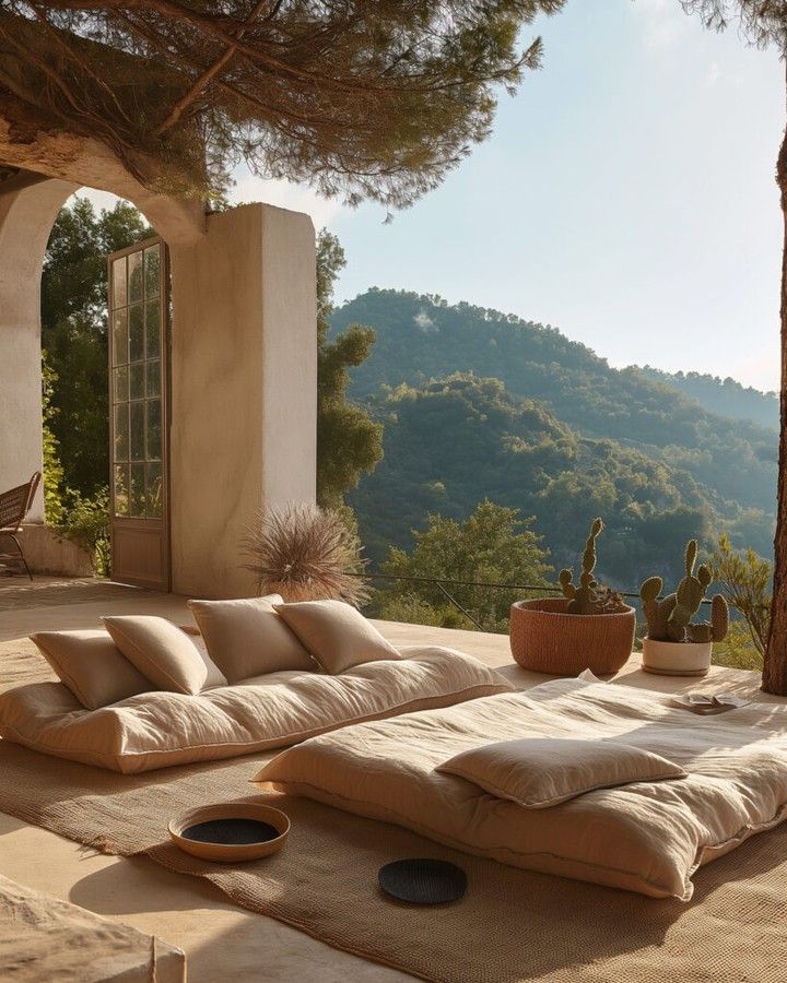 Luxury outdoor lounge area featuring linen floor cushions on a terrace with scenic mountain views.