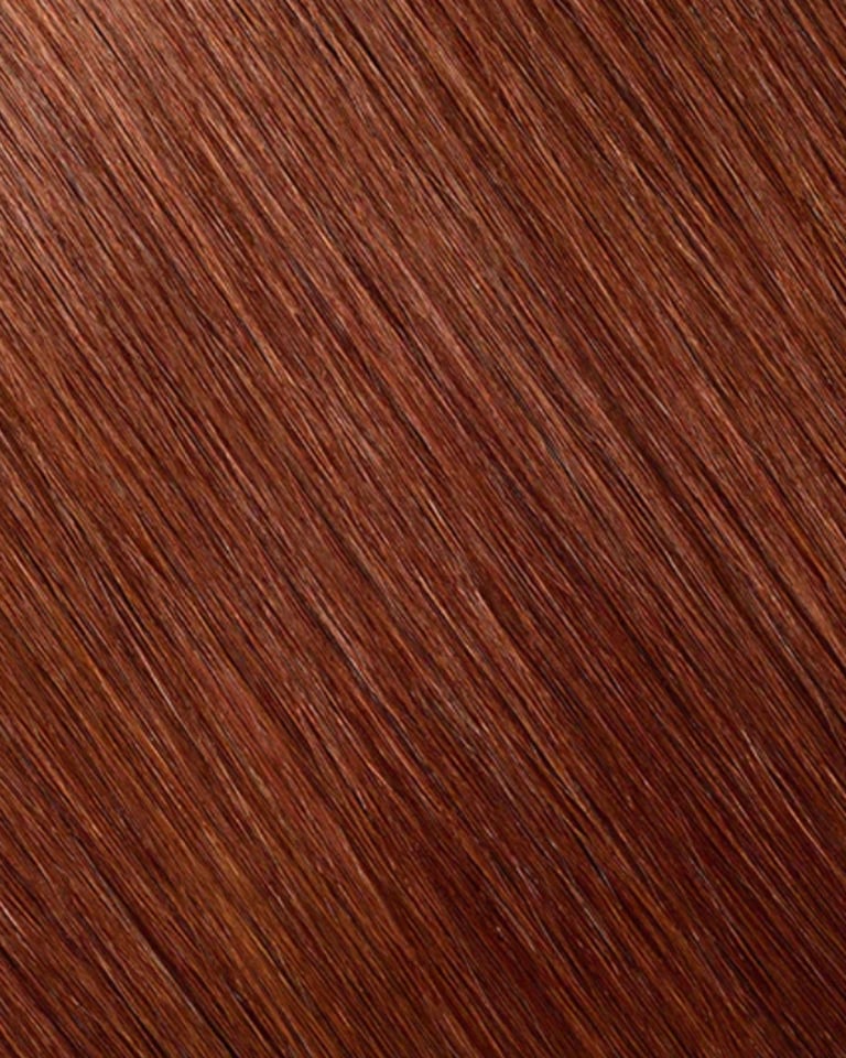 Gros plan de la texture de rallonges de cheveux roux auburn brillants, lisses et parfaitement droite