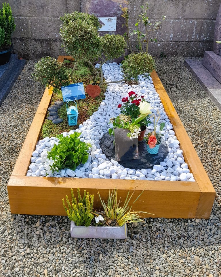 Jardin du souvenir avec cadre bois, décor de galets blancs sinueux et artopierre