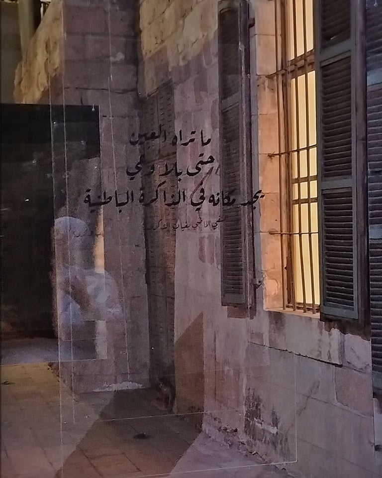 Arabic calligraphy on a glass wall reflecting stone building with shutters luminous spac