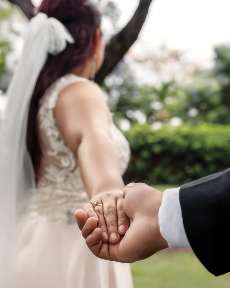 a bride and groom holding hands in a park