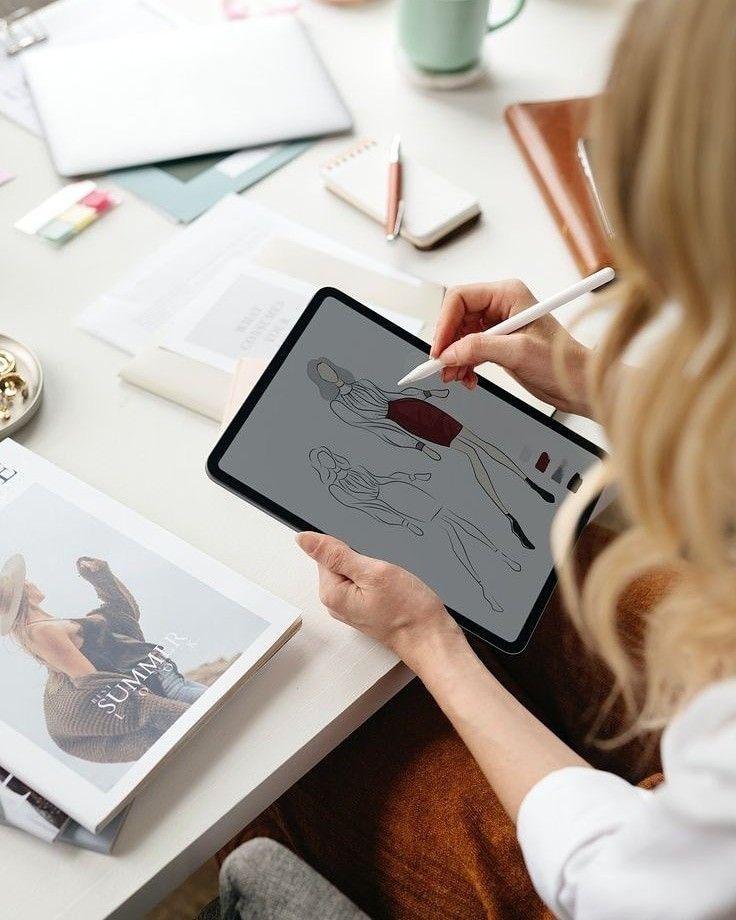a woman sitting at a table with a tablet and a pen