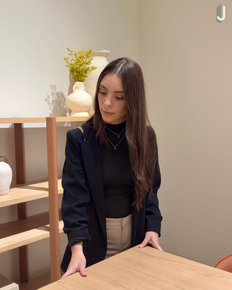 A stylish woman in a black blazer browsing wooden furniture in a modern minimalist home decor store.