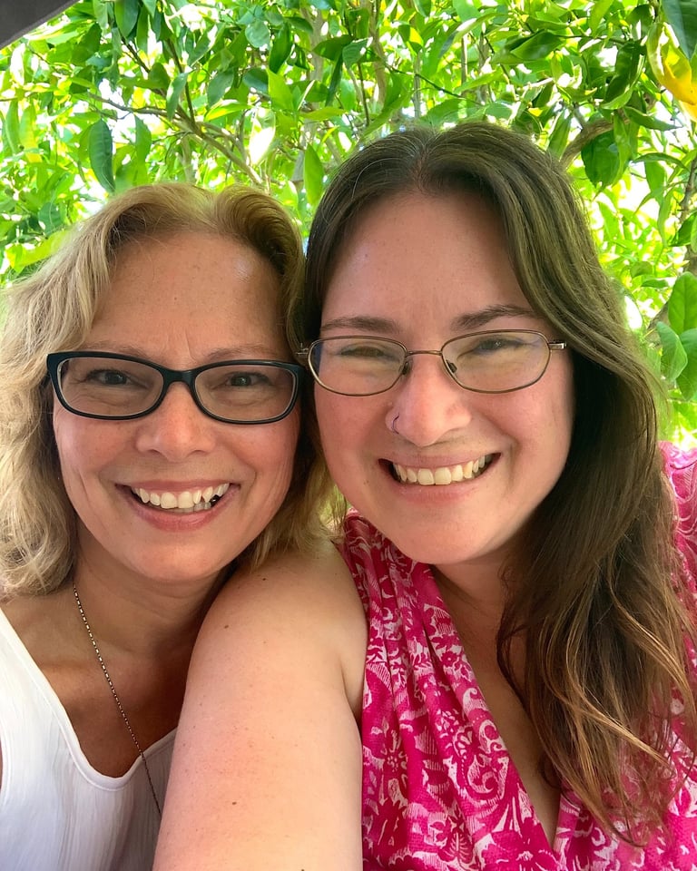 Two women wearing glasses smile at the camera