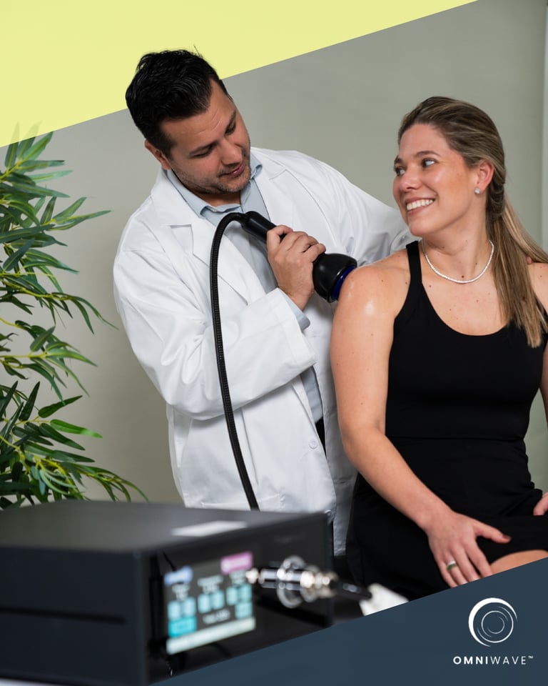 A doctor performing shockwave therapy on a woman's shoulder using an Omniwave medical device.
