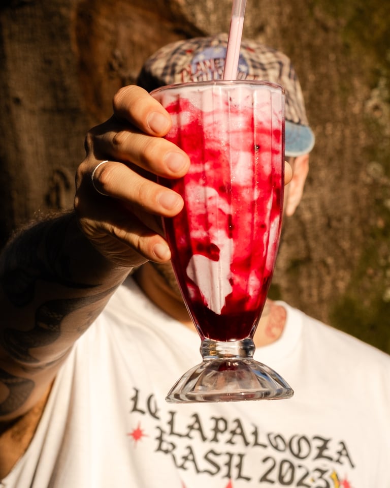 a man holding a milkshake in front of a tree
