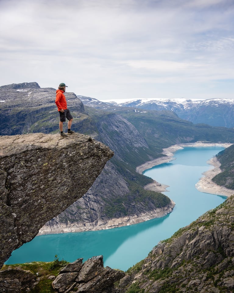 a photo of troltunga mountain in norway with a gree lake