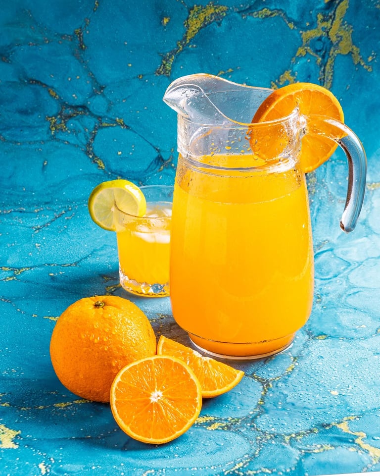 a pitcher of orange juice with oranges and lemon