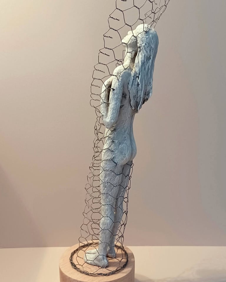 A standing female figure, leaning back and relaxing, surrounded by a wire netting enclosure