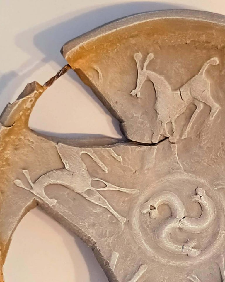 Close up of a bowl-like sculpture with embossed horse figures and symbols in rust/brown hues