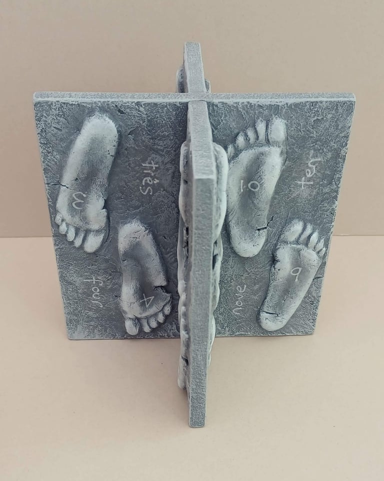 Two intersecting relief sculptures forming an X shape, and depicting three dimensional footprints.