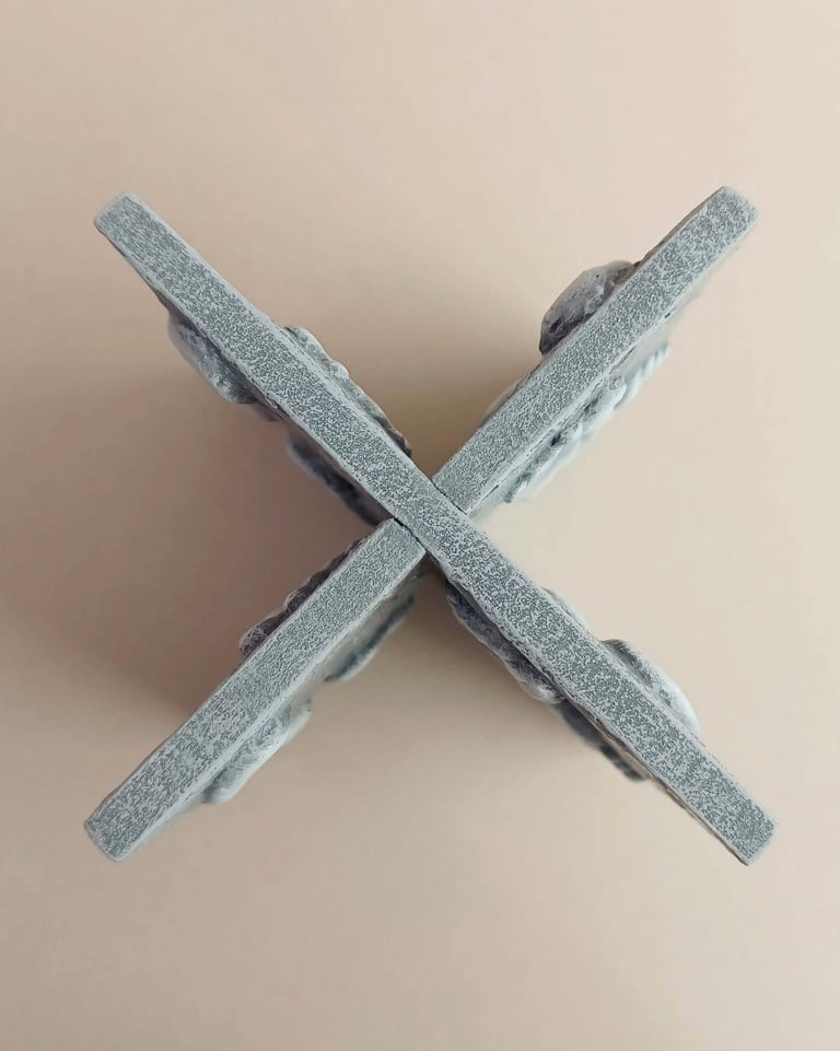 Two intersecting relief sculptures forming an X shape, and depicting three dimensional footprints.