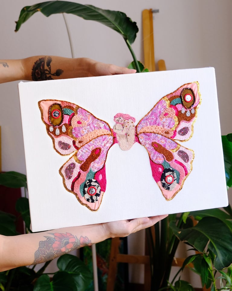 a person holding a butterfly - shaped canvas with a embroidered butterfly