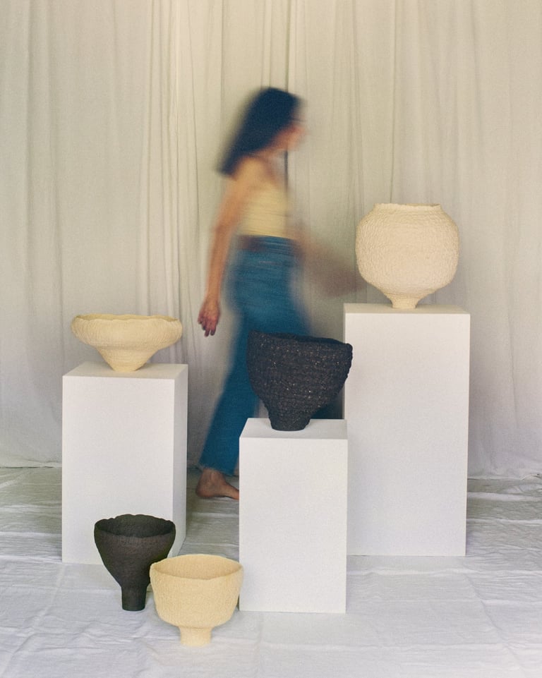 Sabine Segura marchant derrière les sculptures en grès de la série de céramiques Kairos