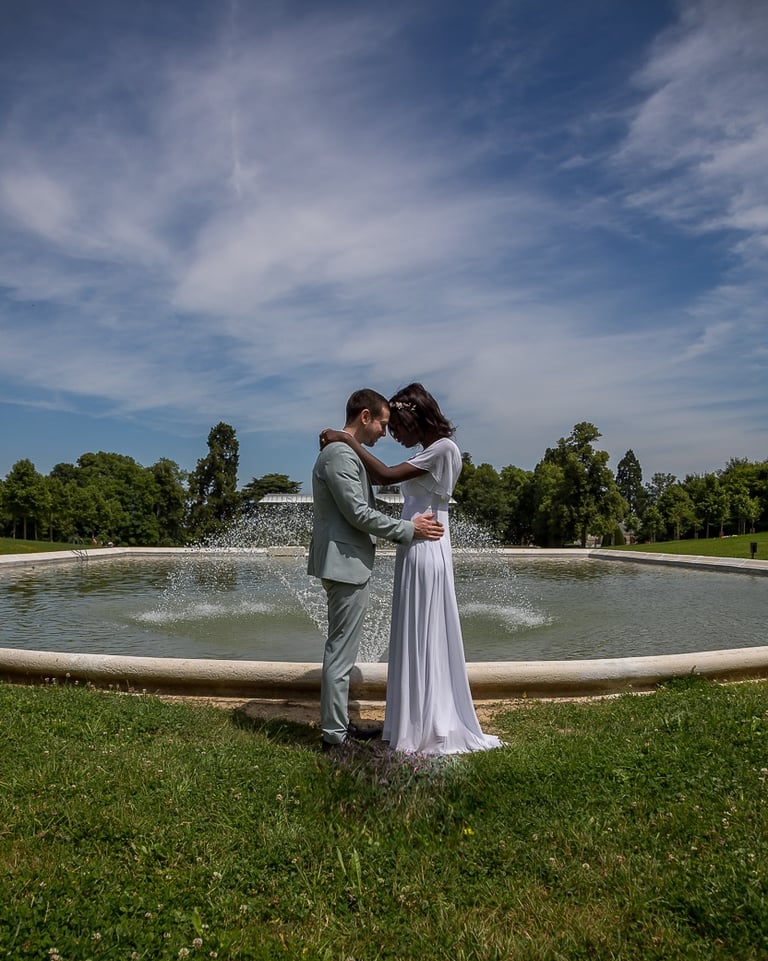 Photo des mariées les yeux dans les yeux devant une fontaine