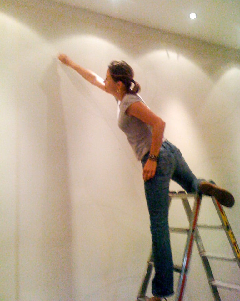 Stefanie on ladder sketching a mural.