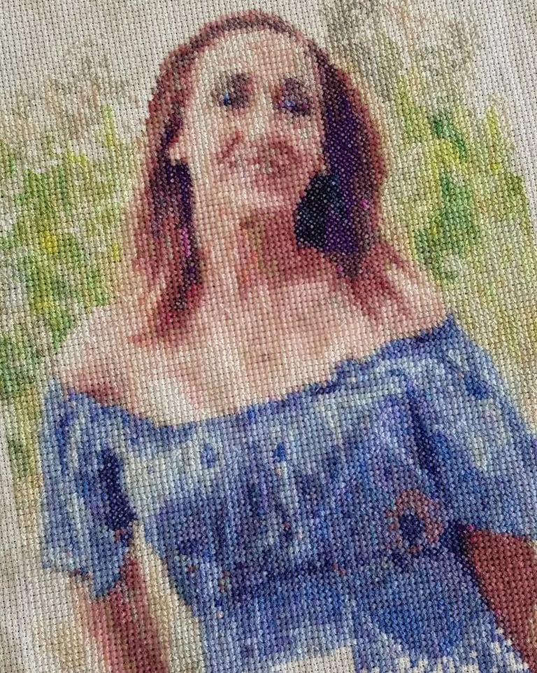 Retrato detallado y personalizado en punto de cruz de una mujer sonriente con un vestido azul  