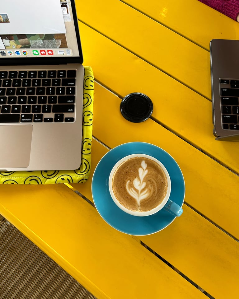 a laptop computer and a cup of coffee on a yellow table