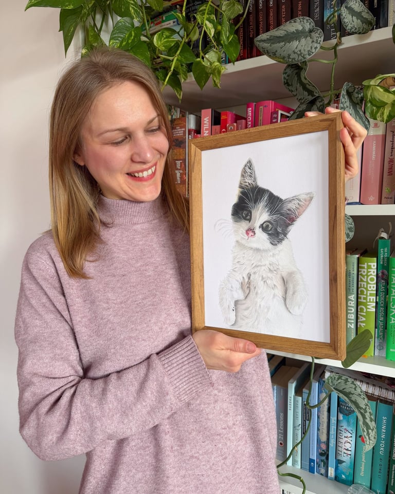 Pet portrait artist holding a framed realistic hand drawn custom cat drawing