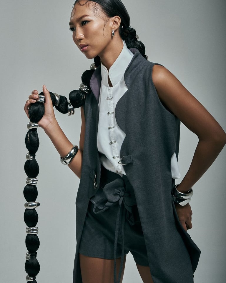 Model in structured Korean-inspired clothing poses while holding her long hair.