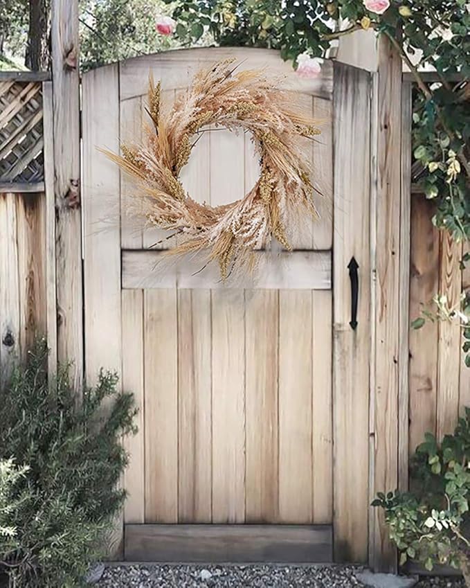 Neutral fall wreath made of dried wheat and grasses hanging on a wooden garden gate