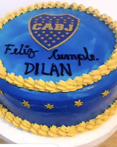 Un pastel de cumpleaños temático de Boca Juniors azul y amarillo con un logotipo de CABJ y glaseado 