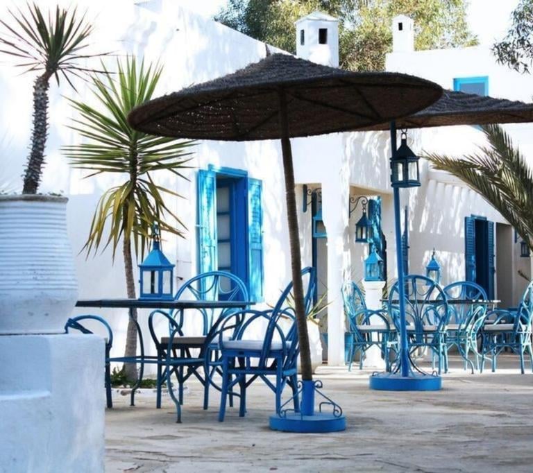 a table with chairs and umbrellas in front of a white building