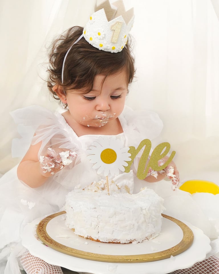 Adorable baby covered in frosting, enjoying a colorful cake smash birthday photoshoot.