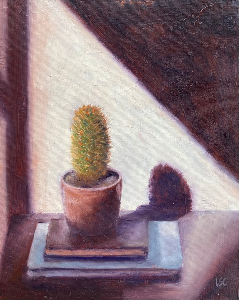 An original oil painting of a small cactus in a pot sitting on book on a sunlit ledge