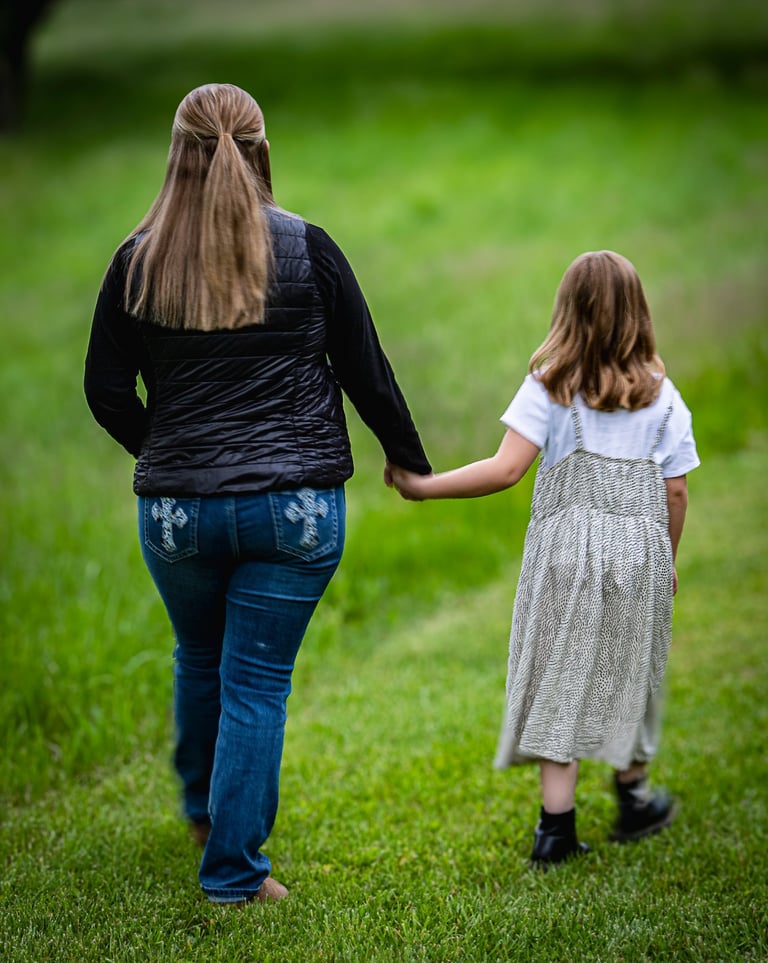Woman and child holding hands while walking in a grassy field. Glouster_Ohio.jpg
