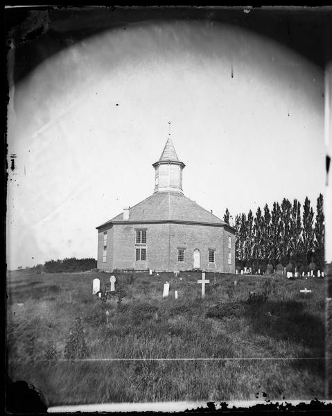 An octagonal church building with a graveyard in black and white