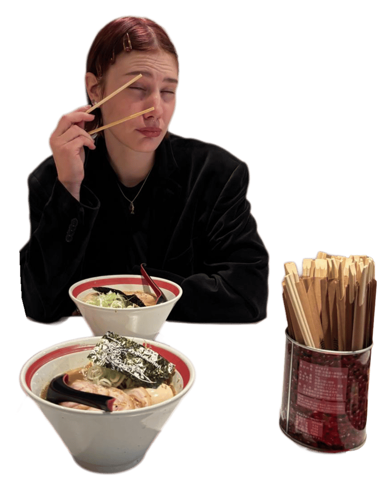 A woman holding chopsticks over bowls of Japanese tonkotsu ramen with seaweed and green onions.
