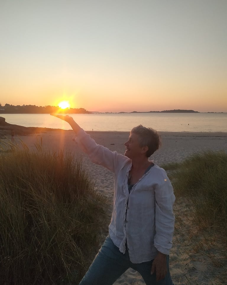 a woman is standing on a beach with her arms outstretched out to the sun
