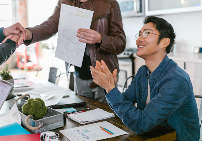 a man in a blue shirt is holding a paper with a paper clipping on