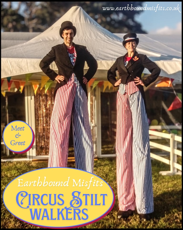 Professional circus stilt walkers in red and blue striped trousers performing at an outdoor event.