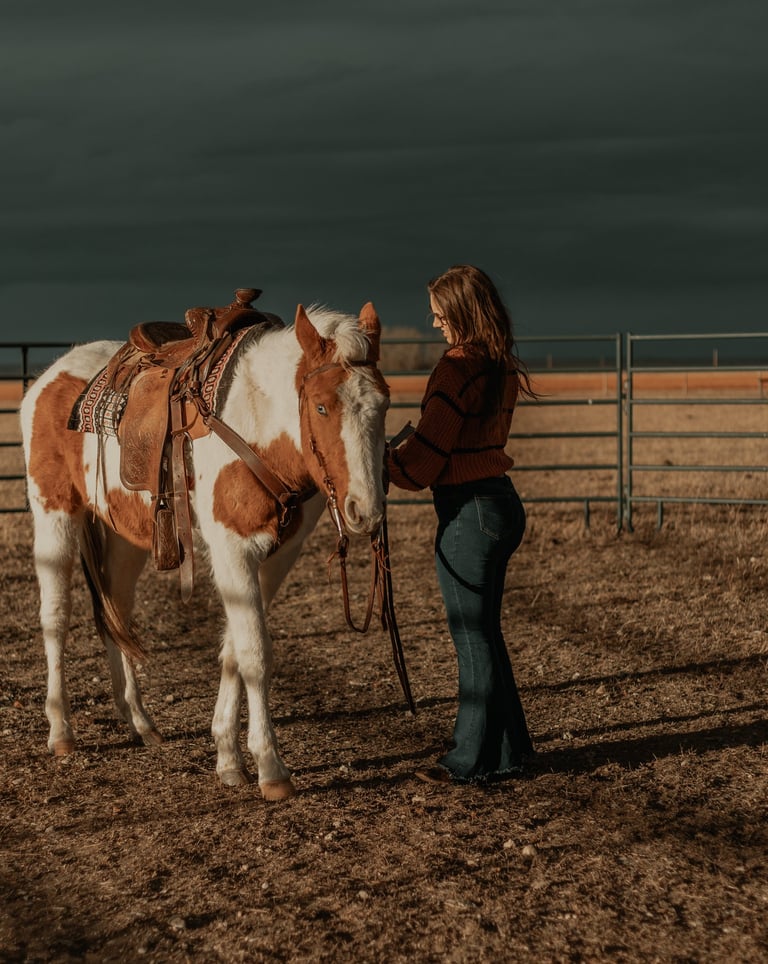 a woman is saddling a paint horse
