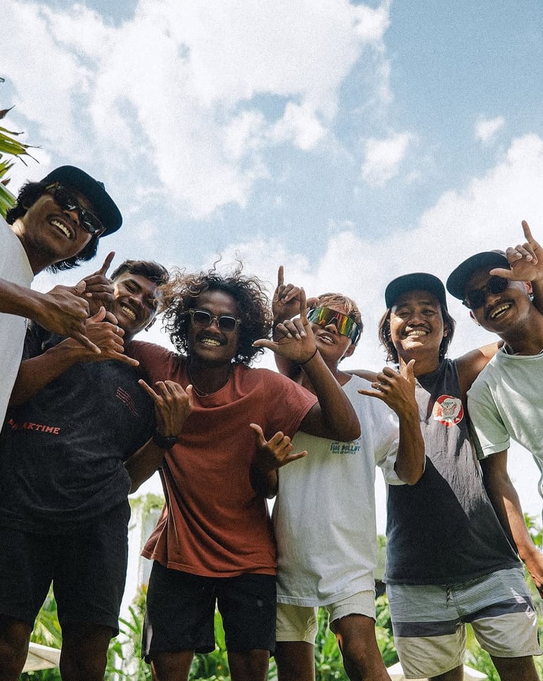 The team giving shaka signs against a bright blue sky.