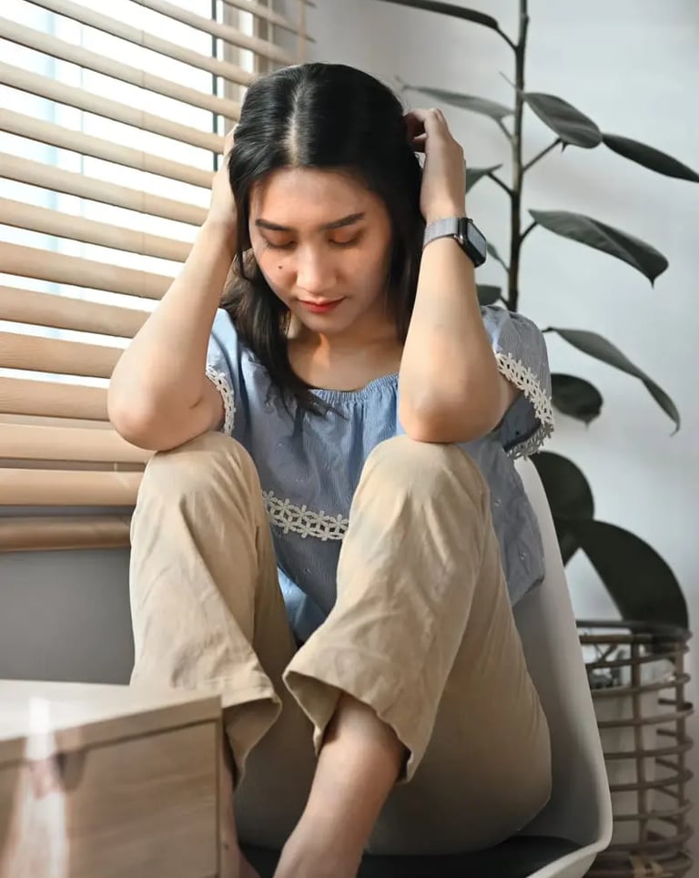 Girl sitting worried on a chair with hands around her head