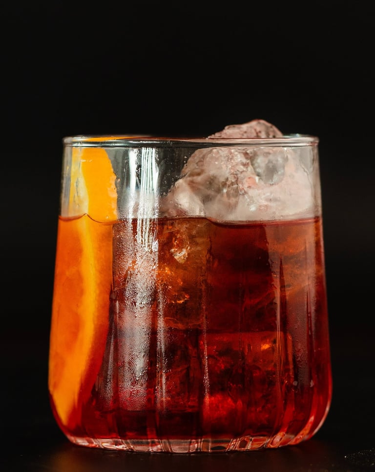 Ein perfekt angerichteter Negroni-Cocktail in einem edlen Kristallglas, hervorgehoben durch kristall