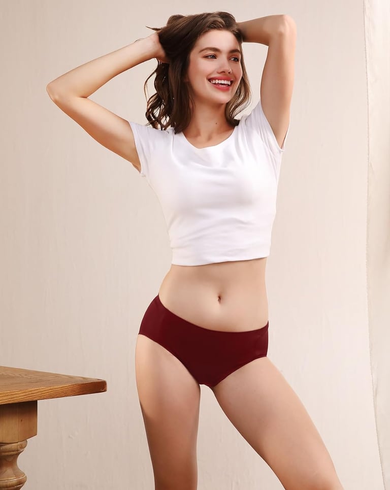 une femme les bras croisé derriere la tète portant un tee short blanc et une culotte rouge . 
