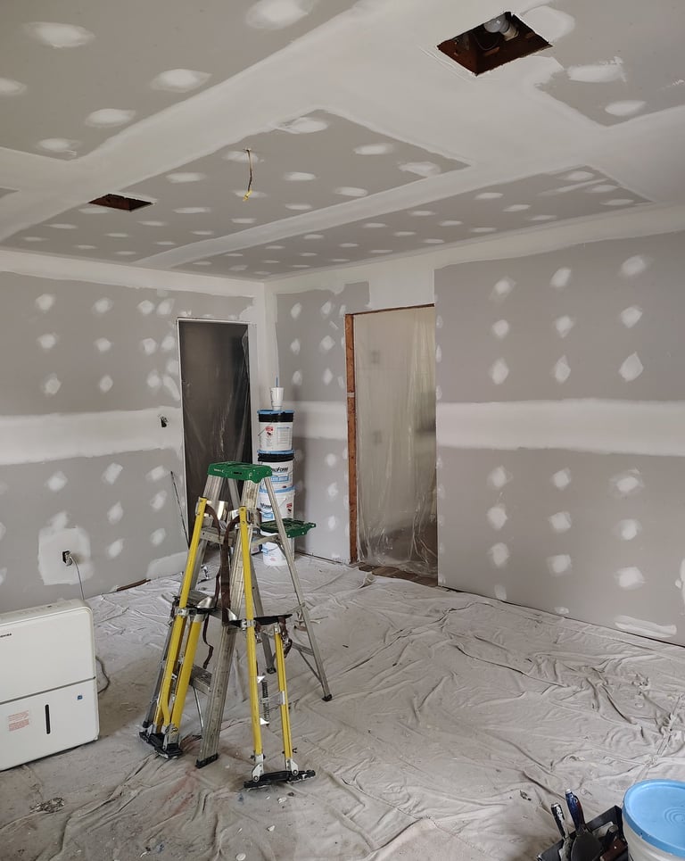 A room that we skim coated with drywall compound with stilts standind up against a ladder.