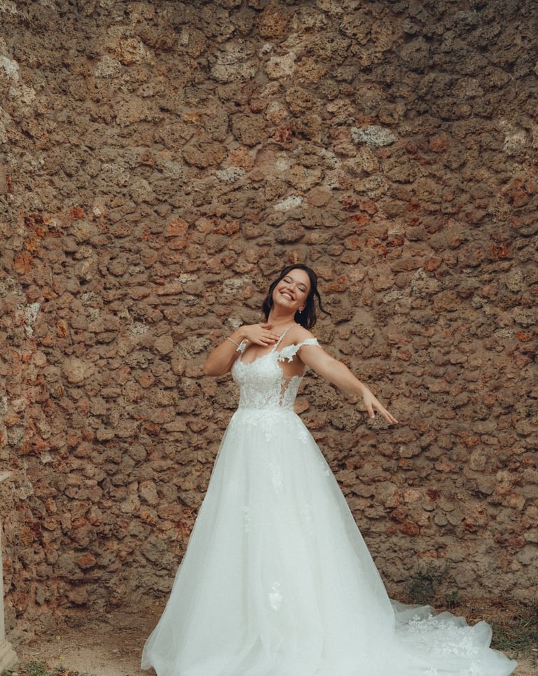 a woman in a wedding dress standing in front of a stone wall