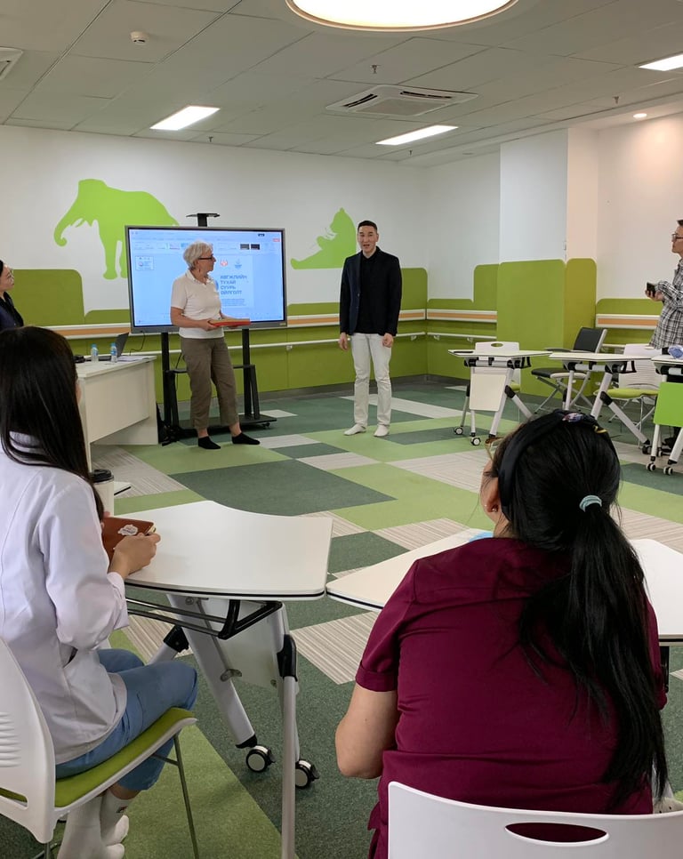 A modern healthcare training room where staff attend a digital presentation on a smart screen.
