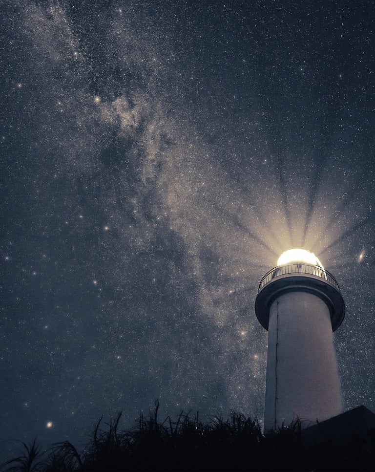a lighthouse at night with a bright light shining through the sky
