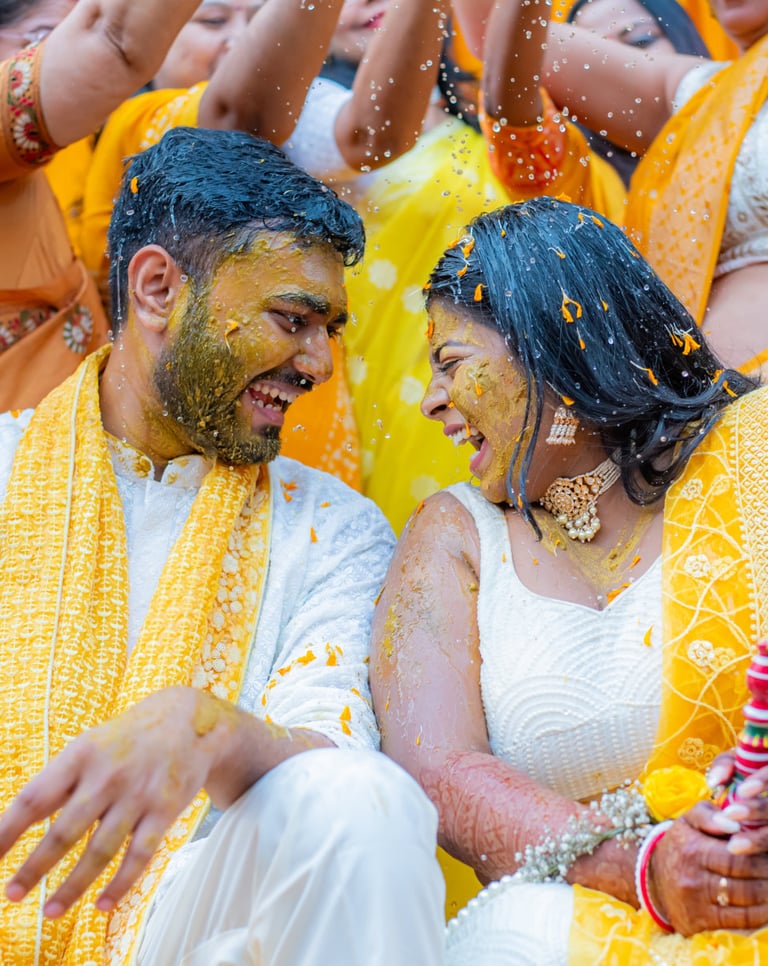Bride and groom with yellow turmeric, smiling.
