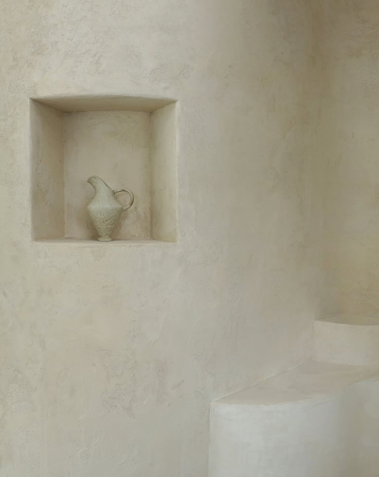 Plastered wall with an architectural niche and a handcrafted pot.