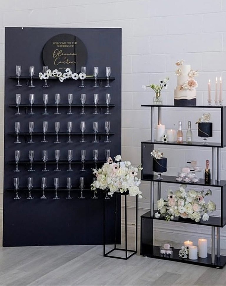 Black champagne wall with champagne flutes white floral. This set up was featured on wedluxe 