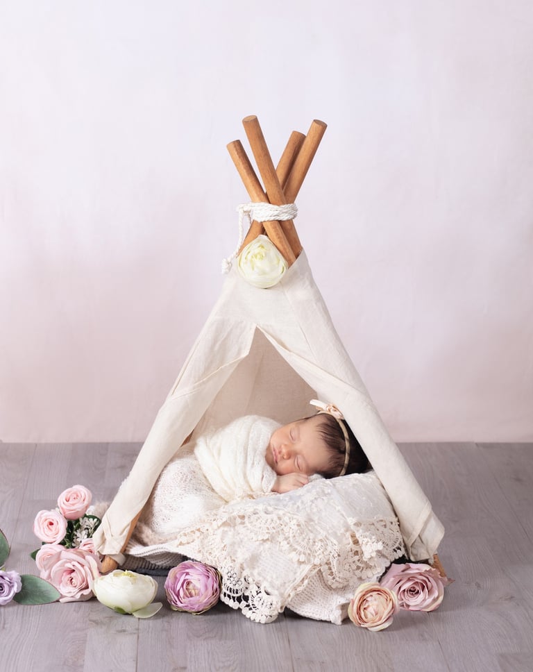 una bebé dormida en una casita apache rodeada de flores