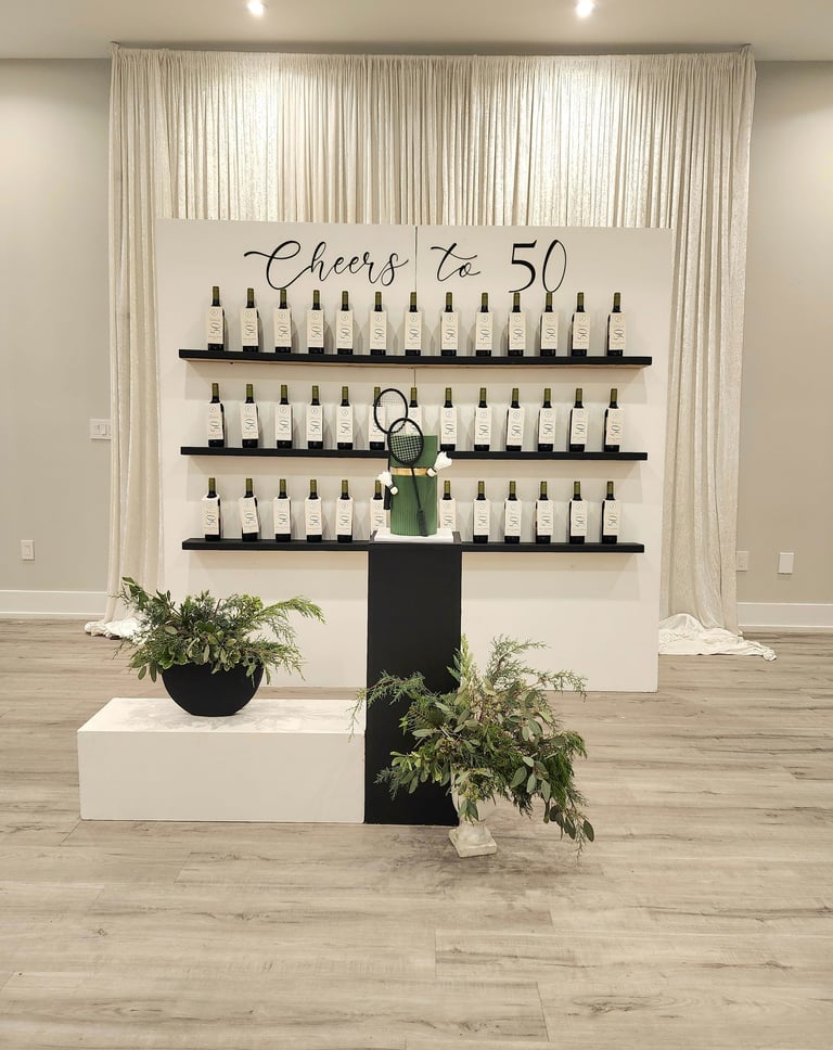 a backdrop display of wine bottles as a favor wall for a 50th birthday celebration