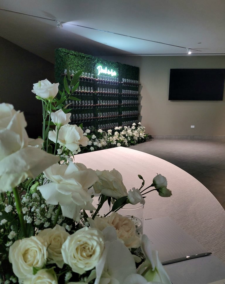 3x champagne walls with 145 champagne flutes a drunk in love neon sign and a floor floral arrangemen